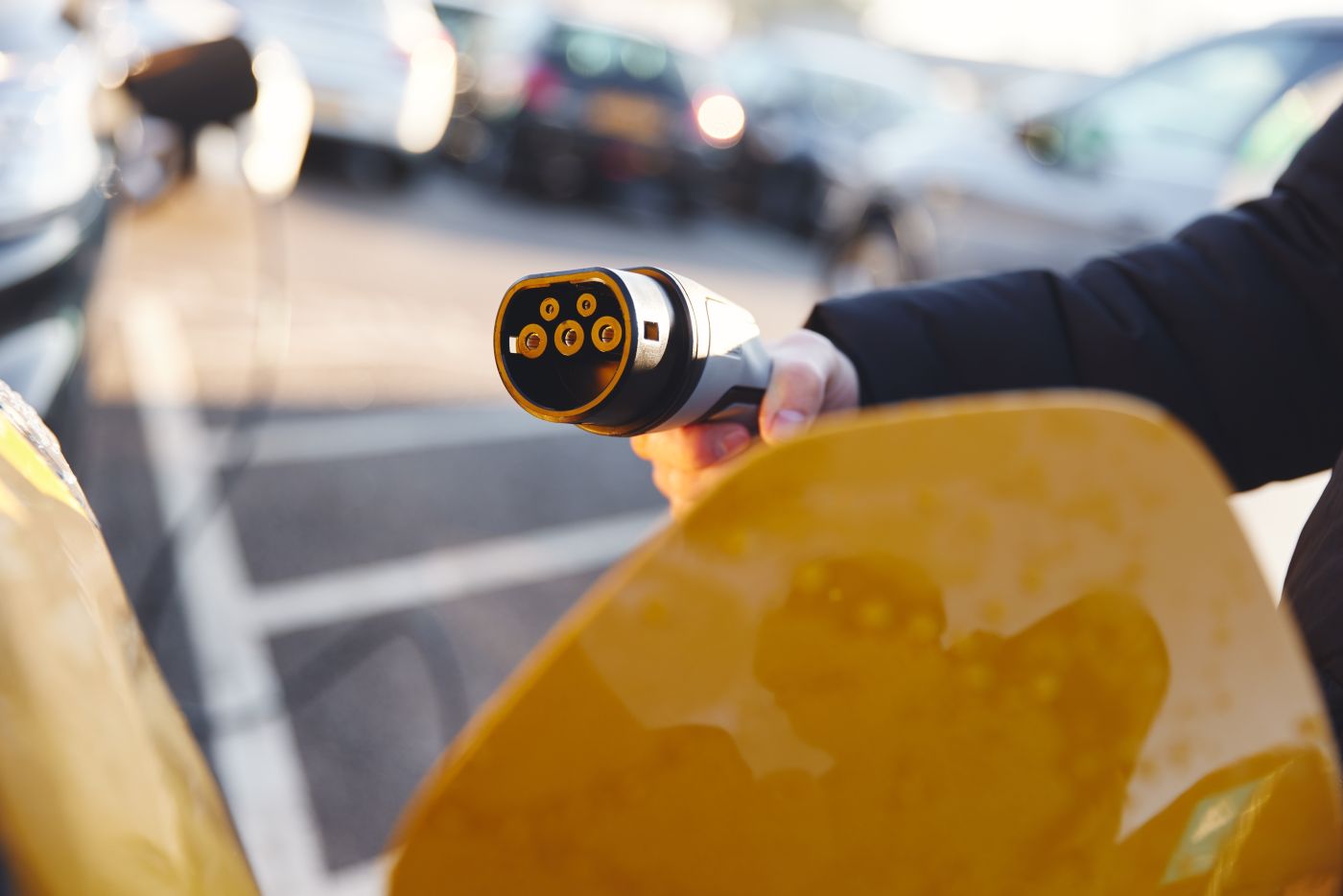 persona con un cargador de coche eléctrico en la mano